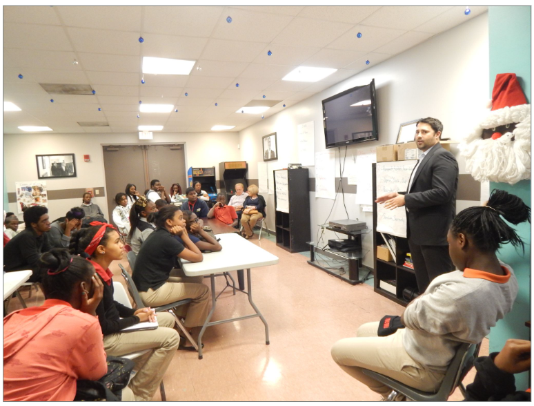 A TECKpert team member presenting to a room of students at a community mentoring session.